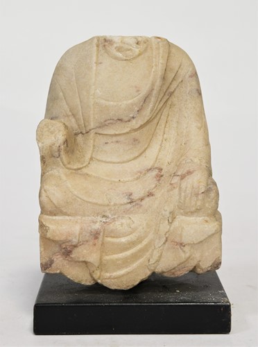 Lot 105 - A mottled white marble seated headless Buddhist deity, perhaps 6th/7th century
