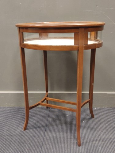 Lot 556 - An oval glass topped display table on outswept...