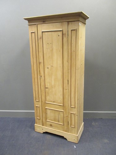 Lot 460 - A pine single wardrobe raised on bracket feet,...