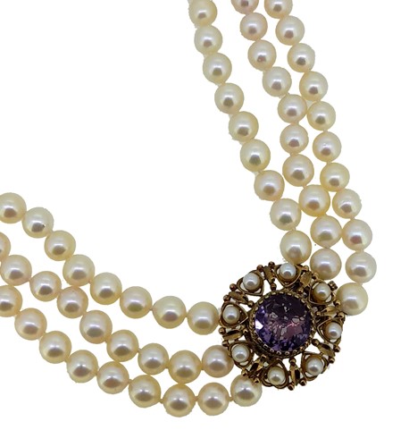 Lot 103 - A three row pearl necklace with an amethyst clasp