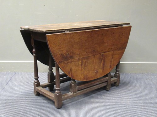 Lot 556 - An oak gate leg table on turned supports...