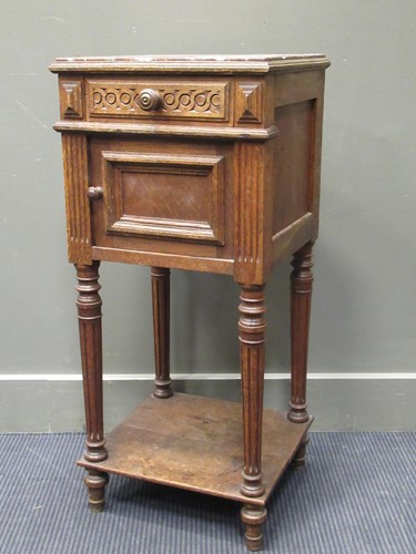 Lot 323 - A carved oak bedside cabinet with rouge veined...