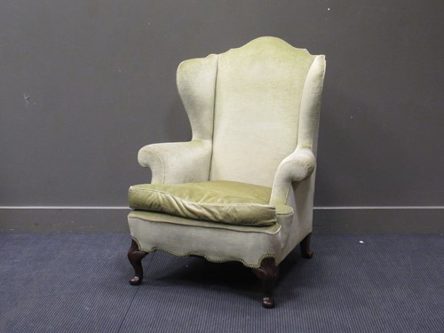 Lot 453 - A fireside wingback armchair on shell carved...