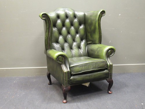Lot 426 - A wing back armchair upholstered in green faux-...