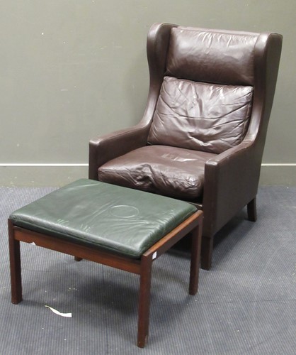 Lot 546 - A modern brown faux leather wing back armchair together with a stool (2)