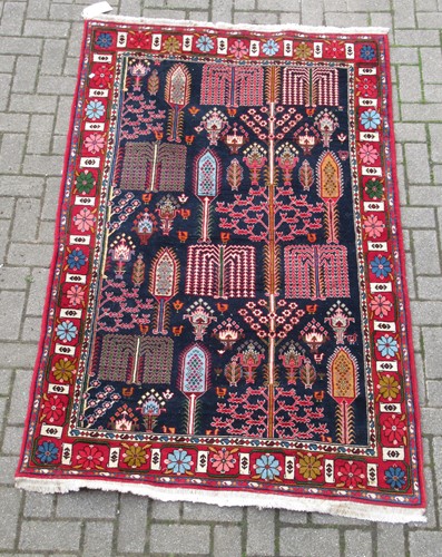 Lot 553 - A hand-woven blue ground rug with floral decoration