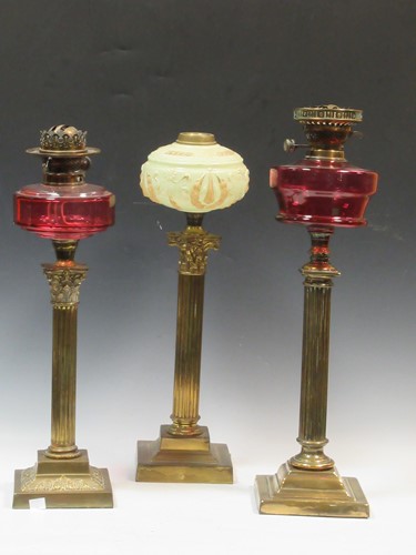 Lot 62 - Three brass oil lamps, two with red glass...