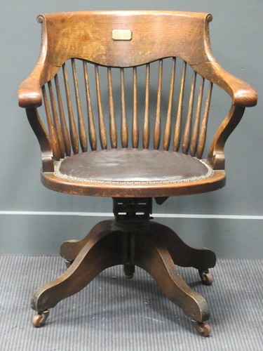 Lot 492 - An oak swivel desk chair back applied with...