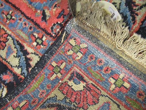 Lot 504 - A large red ground rug with repeating floral...
