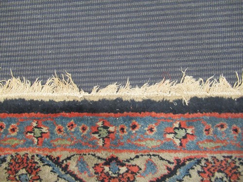 Lot 504 - A large red ground rug with repeating floral...