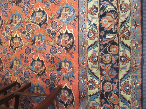 Lot 504 - A large red ground rug with repeating floral...