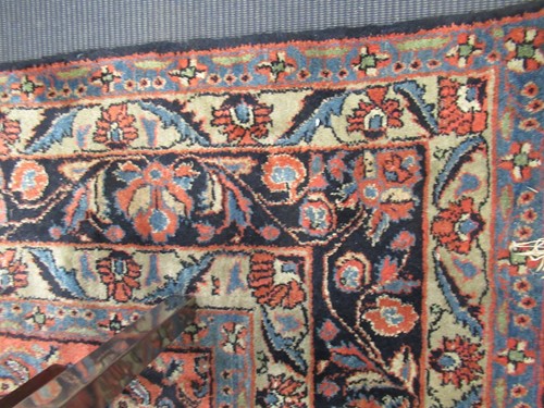 Lot 504 - A large red ground rug with repeating floral...
