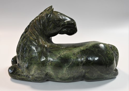 Lot 430 - A Chinese spinach jade type recumbent horse, Ming style