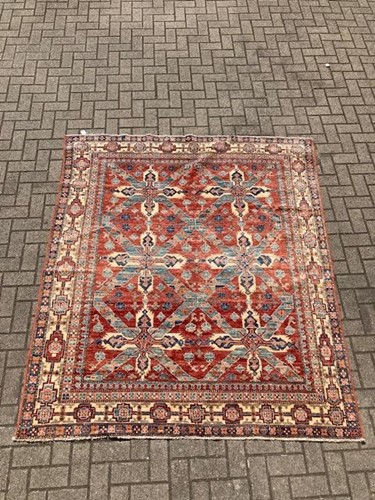 Lot 565 - A red ground geometric pattern wool rug with...