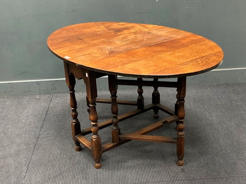 Lot 386 - An oak gateleg table with oval drop flap top,...