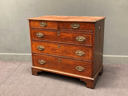Lot 472 - A George III oak chest of drawers with oval...