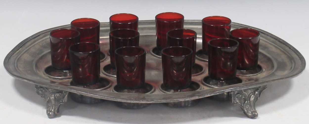 Lot 11 - A pewter shot holder tray with twelve red glasses