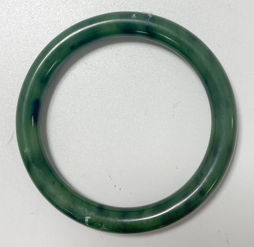 Lot 42 - A Chinese mottled green jade bangle
