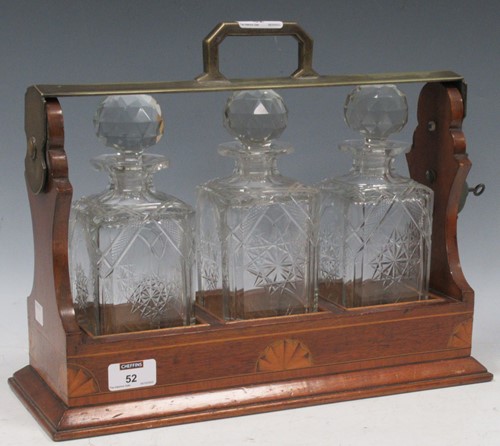 Lot 52 - A tantalus with three cut glass decanter, the...
