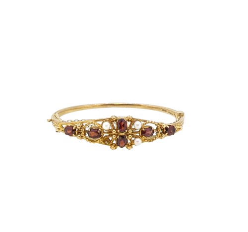 Lot 46 - A late 20th century 9ct gold garnet and pearl hinged bangle