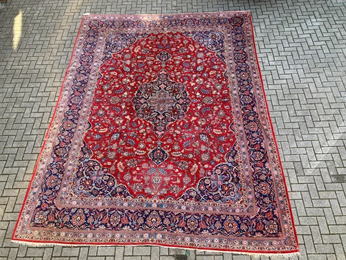 Lot 972 - A red Persian rug decorated with flowers