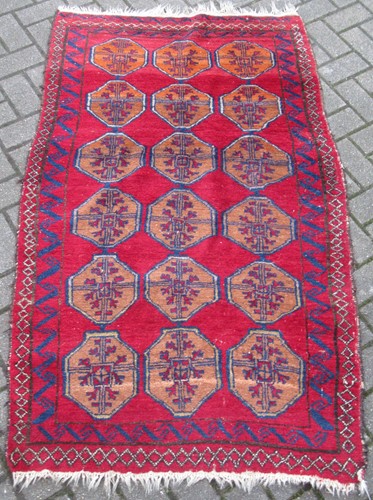 Lot 900 - a red ground woolen rug with orange medallions,...