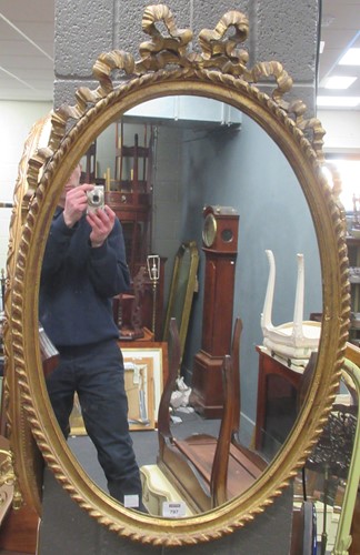 Lot 797 - A giltwood oval wall mirror with ribbon...