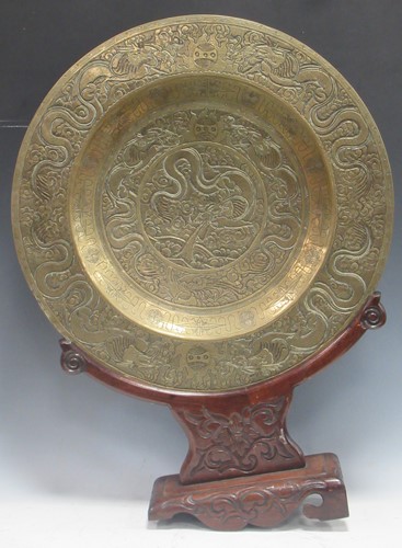 Lot 123 - A Chinese circular brass dish on carved wood...