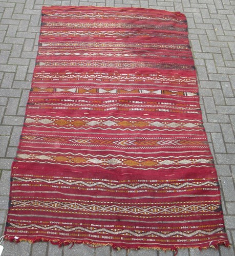 Lot 610 - A red ground tribal runner decorated with...