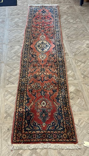Lot 497 - A red ground wool runner with deep pile, blue...