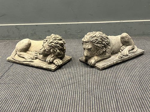 Lot 480 - An opposing pair of cast stone recumbent lions...