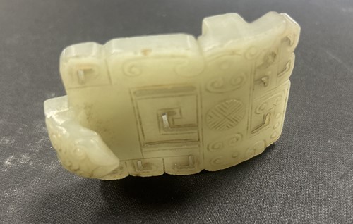 Lot 29 - A Chinese light green jade archaic style belt buckle, Qing Dynasty, 19th century