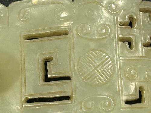 Lot 29 - A Chinese light green jade archaic style belt buckle, Qing Dynasty, 19th century