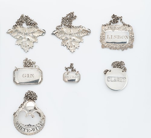 Lot 307 - A collection of 7 George III and later silver bottle labels by notable silversmiths