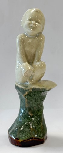 Lot 23 - An unusual Doulton Lambeth model of a young child perched upon a rock