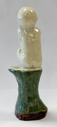 Lot 23 - An unusual Doulton Lambeth model of a young child perched upon a rock