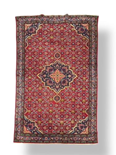 Lot 730 - A Persian design red ground wool rug with...