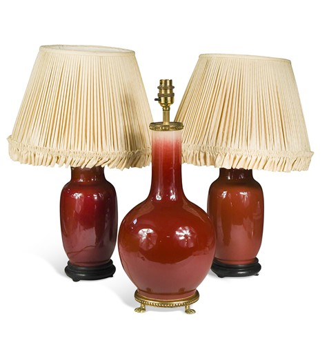 Lot 472 - A group of three sang de boeuf glazed pottery lamps, 20th century