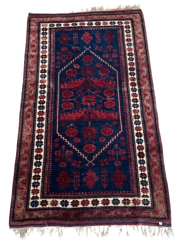 Lot 724 - A Beluchi rug in deep red and dark blue with...