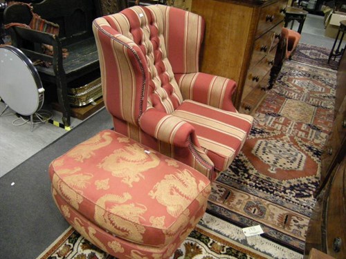 Lot 125 - An upholstered wing back armchair and a foot...