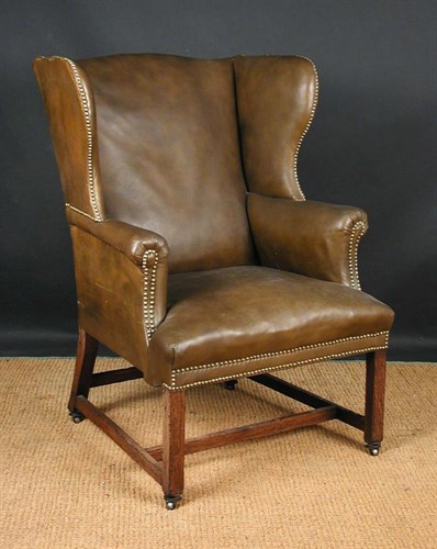 Lot 684 - A George III leather upholstered oak framed wing arm chair