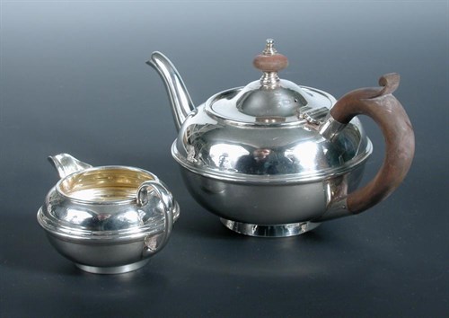 Lot 243 - A small silver teapot and matching cream jug