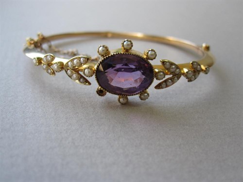 Lot 148 - An Edwardian amethyst and seed pearl hinged bangle