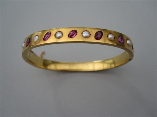 Lot 250 - A Russian 18ct gold, ruby and seed pearl hinged bangle